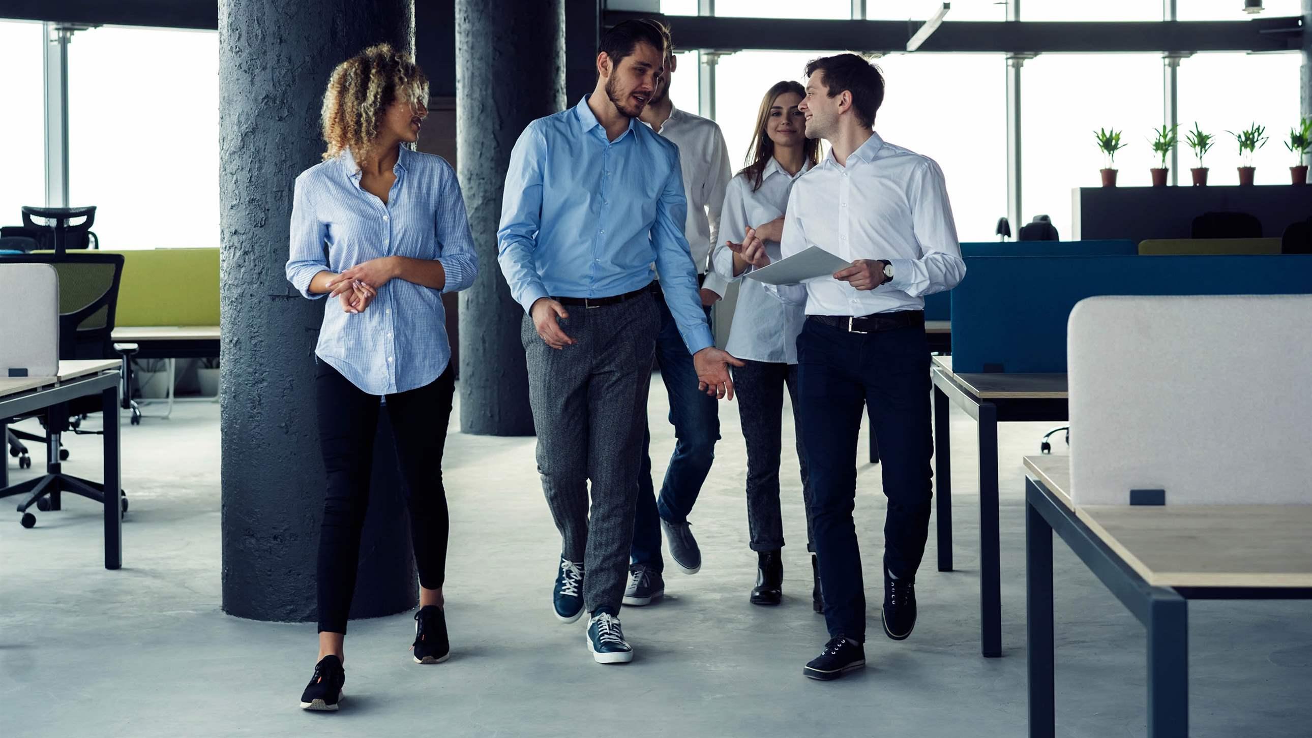 Taking their business on the move. Full length of young modern people in smart casual wear having a discussion while walking through the large modern office