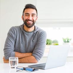 Handsome hispanic man working using computer laptop happy face smiling with crossed arms looking at the camera. Positive person.